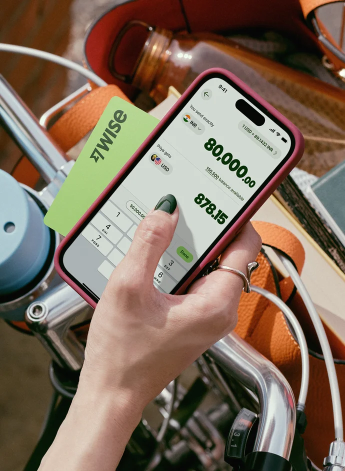 Close-up of person with a Wise card using the Wise mobile app to manage money while on the go.