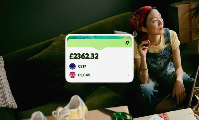 Woman sitting on a green sofa with a Wise app interface showing a balance of £2,862.22.