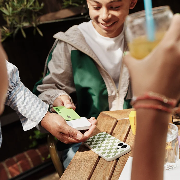 Close-up of a person at a café paying with a Wise card.