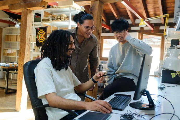 A group of startup employees excitedly looking at a computer