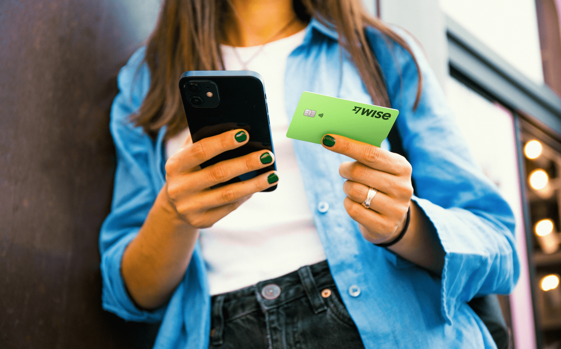 A person holding the Wise card and a phone