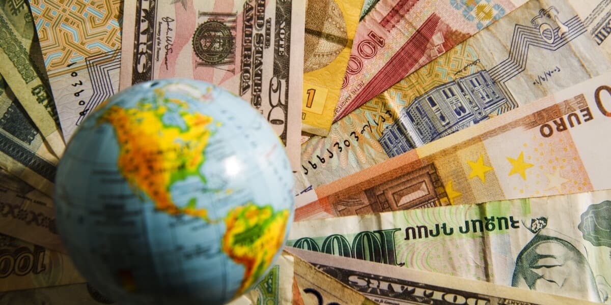 Ein kleiner Globus liegt auf einem Fächer von Geldscheinen aus unterschiedlichen Ländern