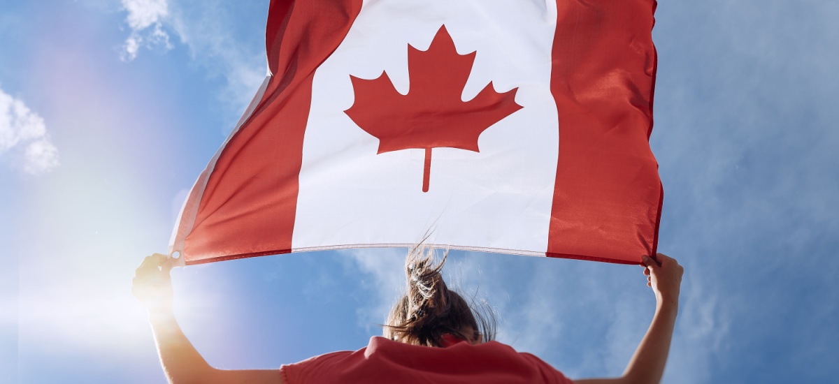 woman holding Canada flag up to the sky