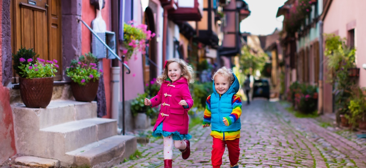 two young children running downa cobbled street