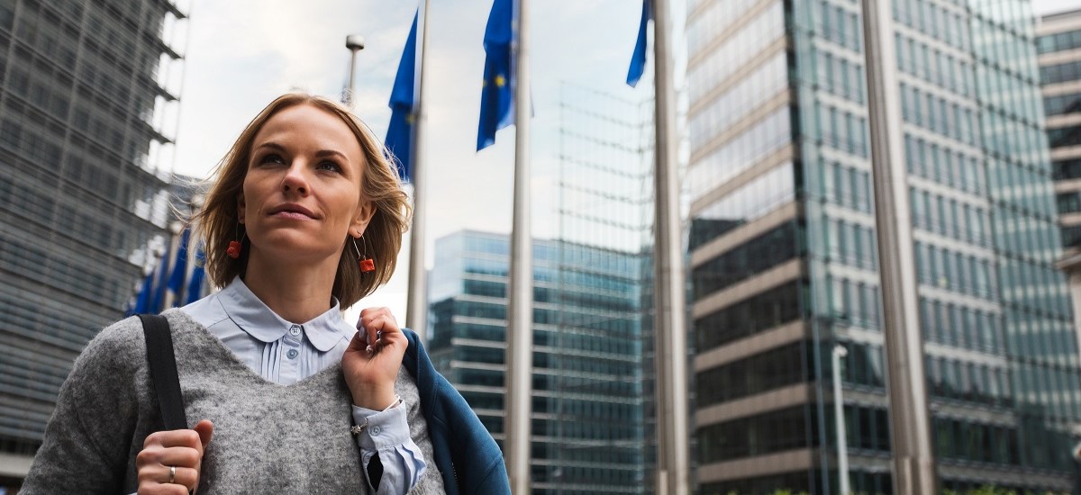 blonde woman in front of building with EU flags