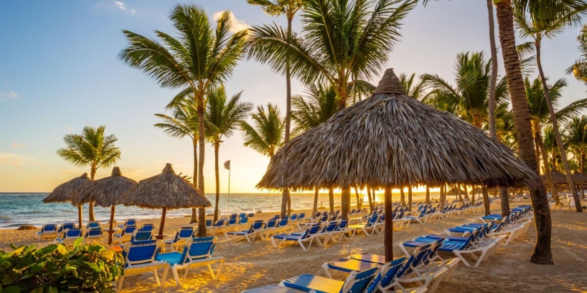 Sandstrand mit Palmen und Sonnenliegen in der Dominikanischen Republik