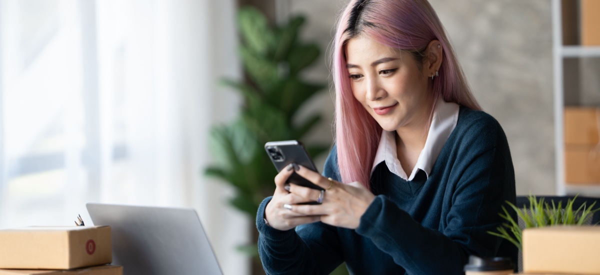 Asian woman with long pink hair looking at her phone