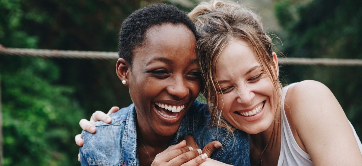 Two women laughing and hugging each other