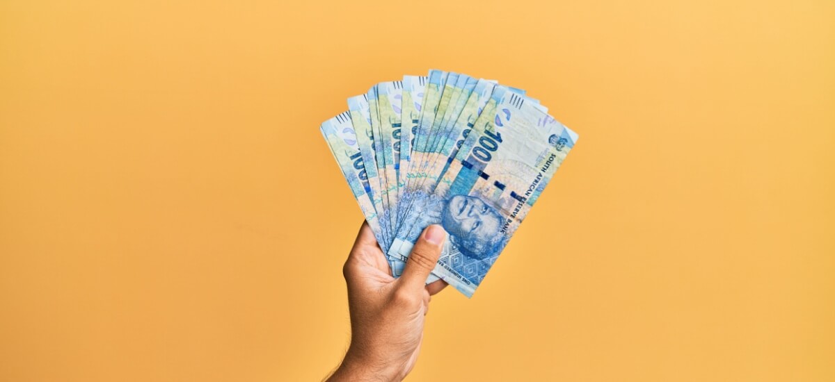 Eine Hand hält ein Bündel südafrikanischer Geldscheine