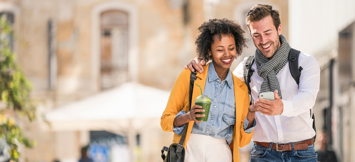 Couple walking to work in Portugal on morning commute, looking at phone