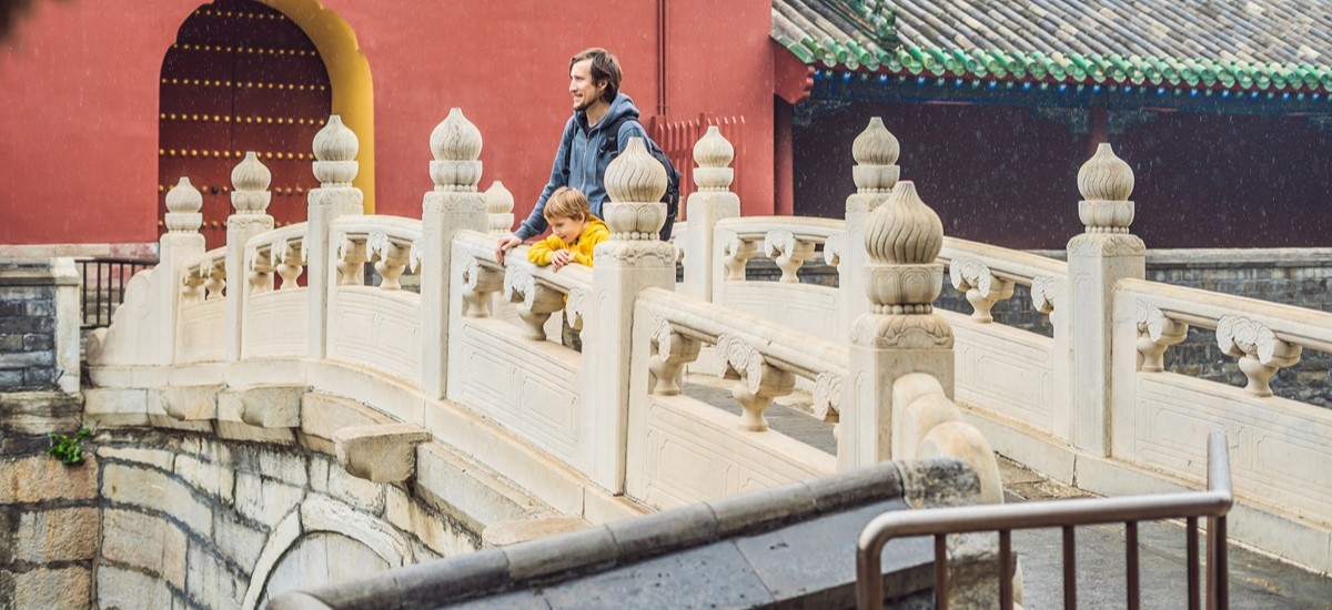 Father and son on a bridge on temple grounds in China