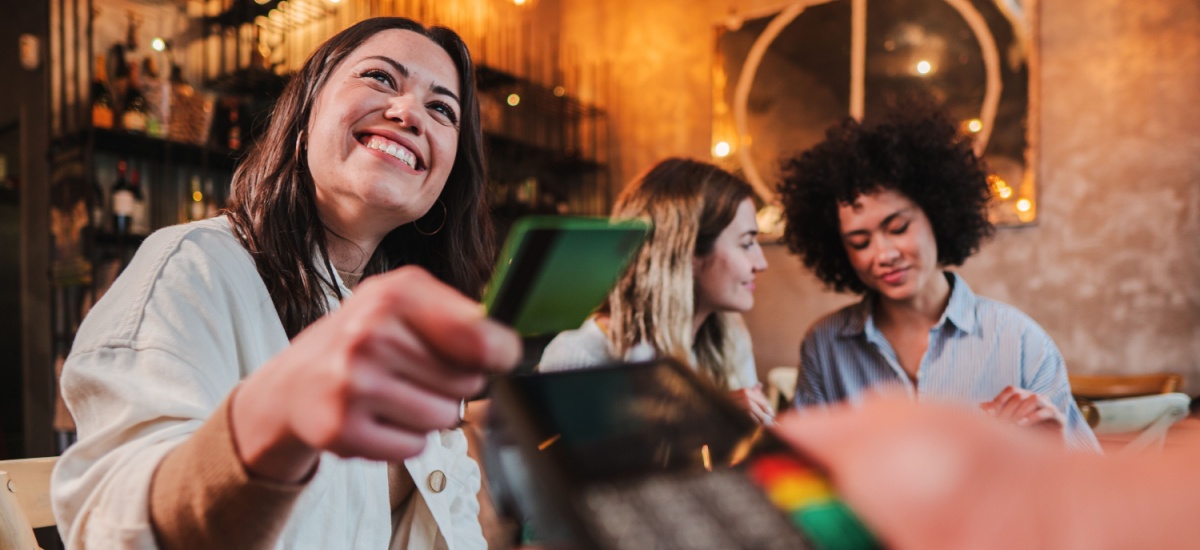 Smiling woman making a contactless payment in a bar/restaurant