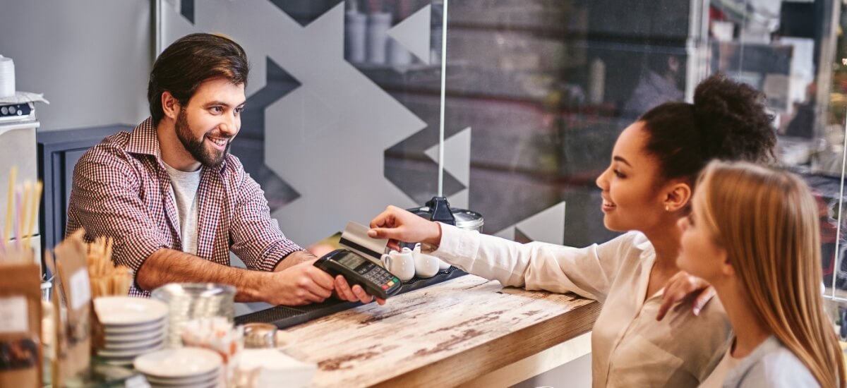 Zwei Frauen bezahlen mit Karte in einem Cafe