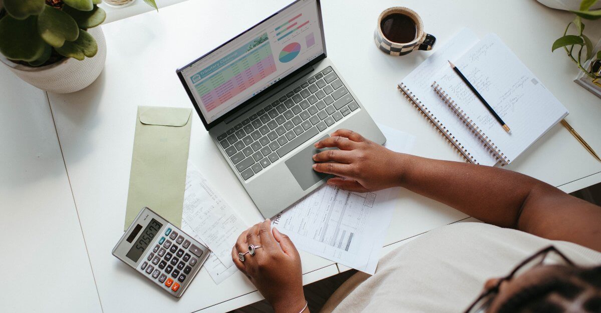person-working-on-reports-with-documents-laptop-and-calculator