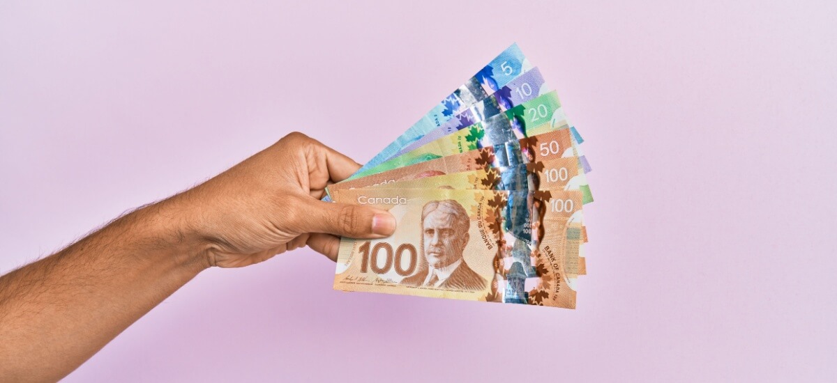 Eine Hand hält ein Bündel kanadischer Geldscheine