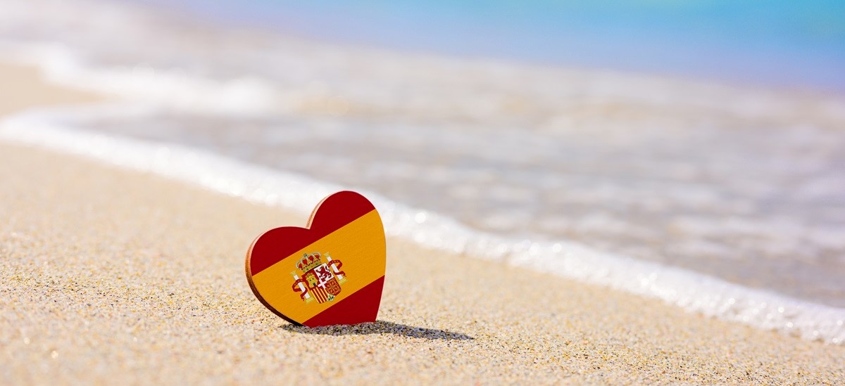 Heart with a spanish flag on it on a beach
