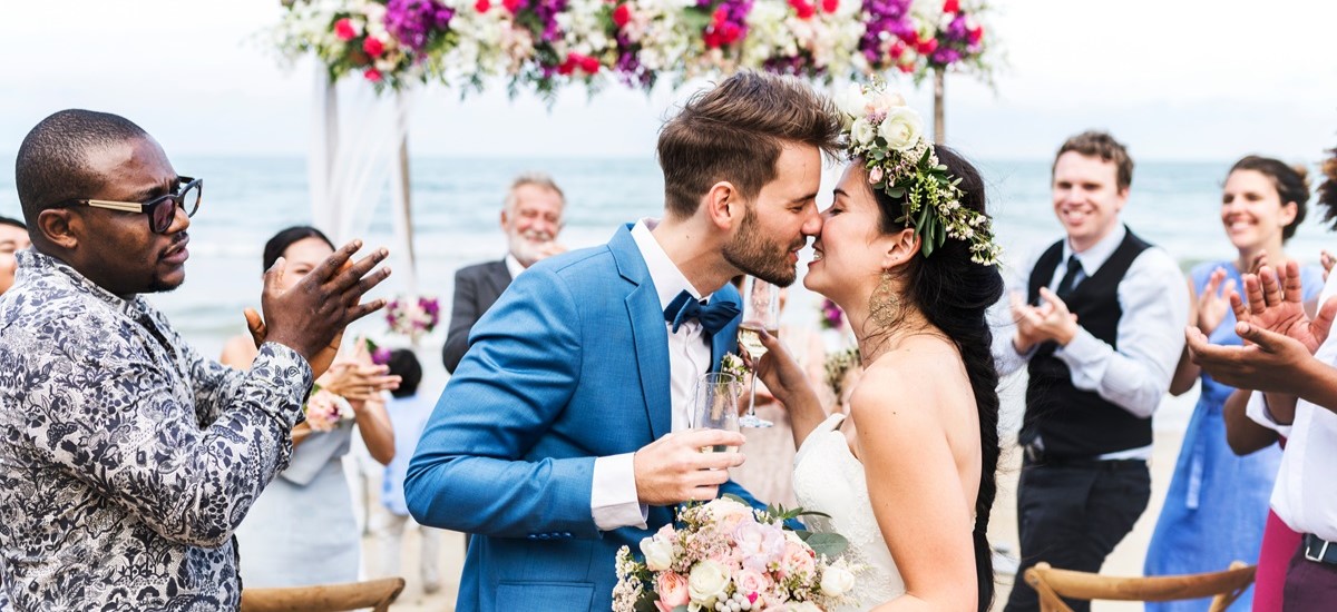wedding ceremony on a beach with bride and groom kissing