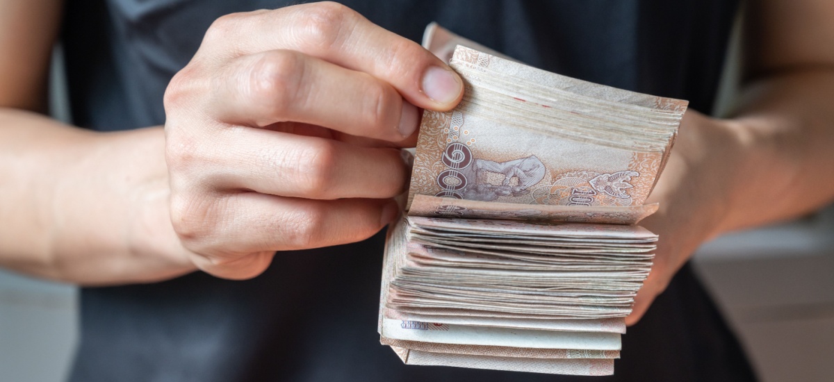 ภาพระยะใกล้ของมือที่กำลังนับเงินบาทจำนวนมาก