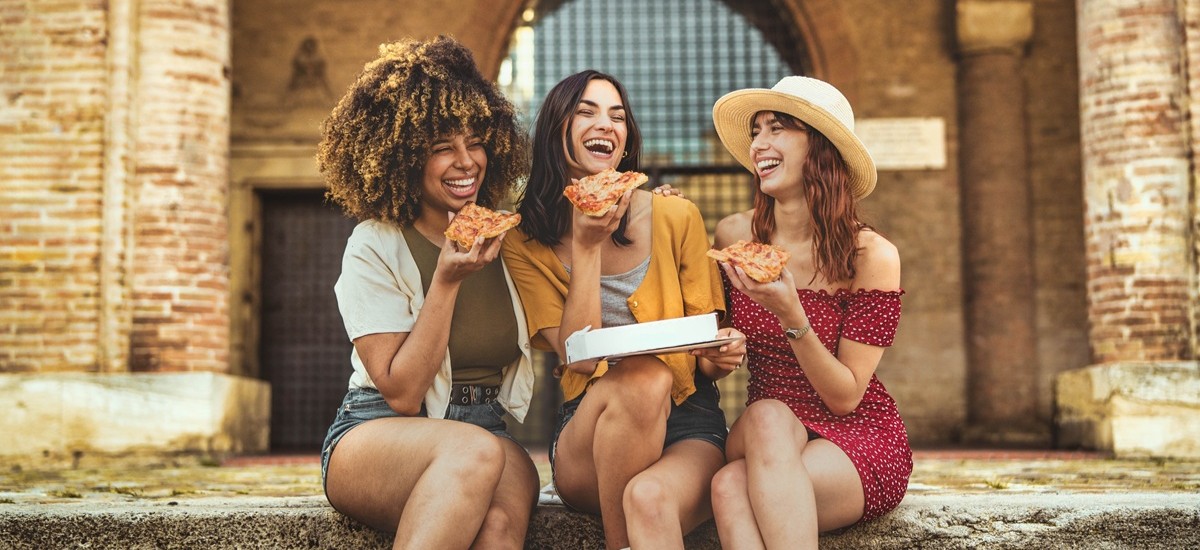 group of friends eating pizza in Italy on steps of old building