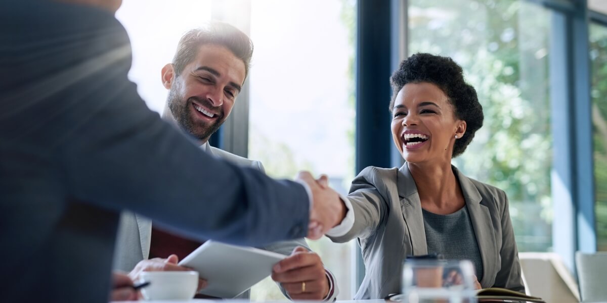Zwei Personen schütteln lächelnd die Hände nach einem erfolgreichen Vertragsabschluss