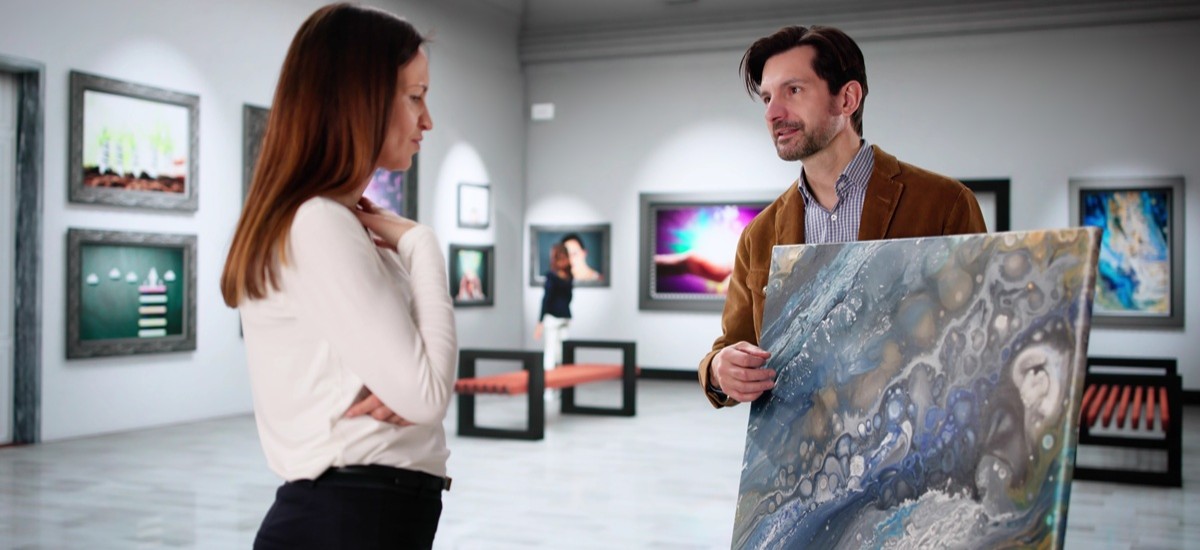 artist showing a potential buyer his art in a gallery