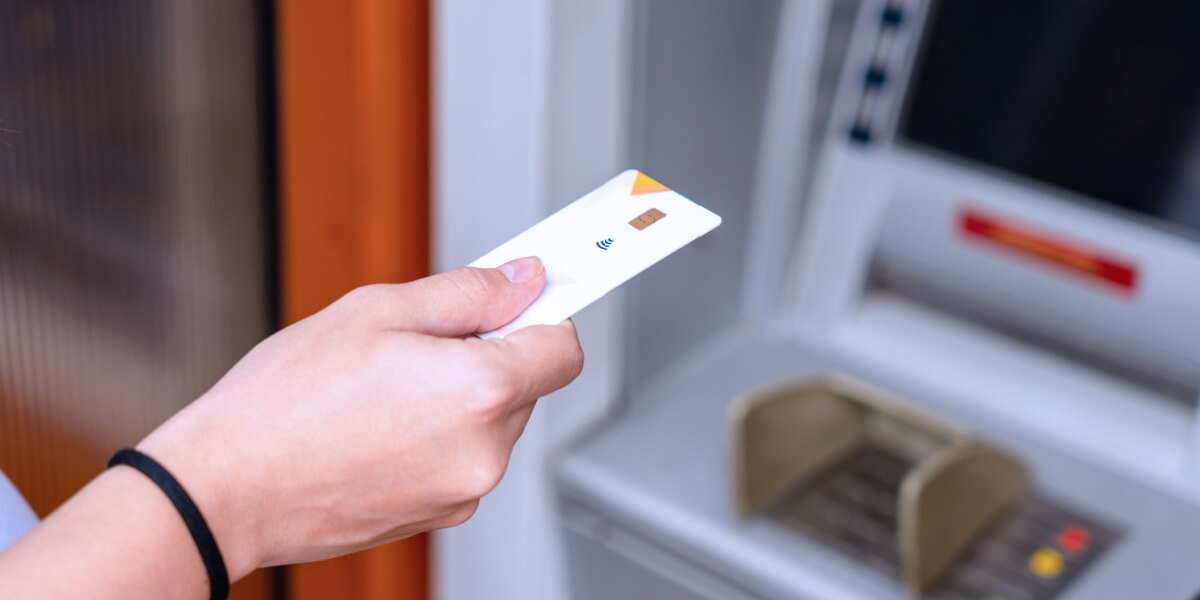 Eine Person mit Kreditkarte an einem Bancomaten