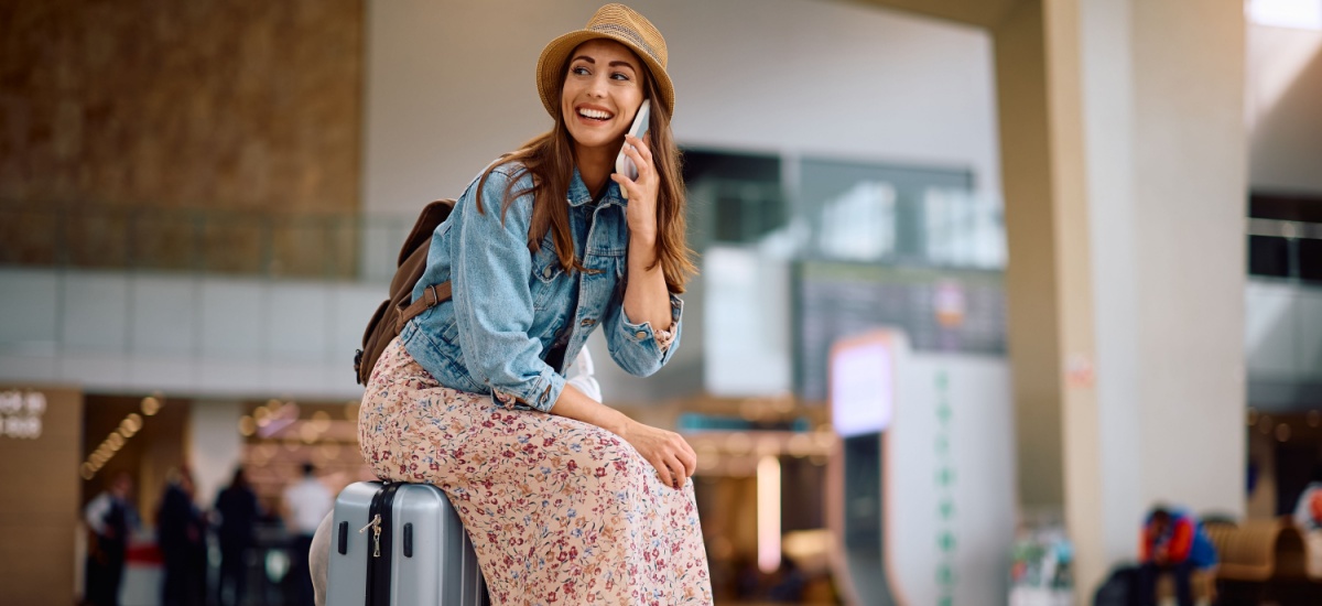 woman-sitting-on-suitcase-talking-on-phone