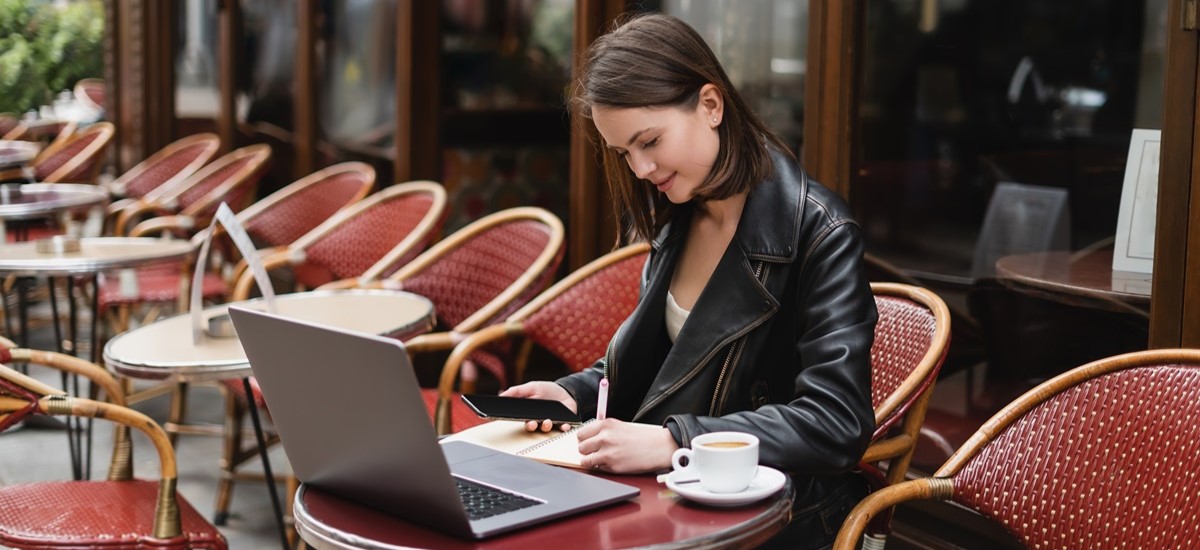 woman working on a laptop outside a French cafe