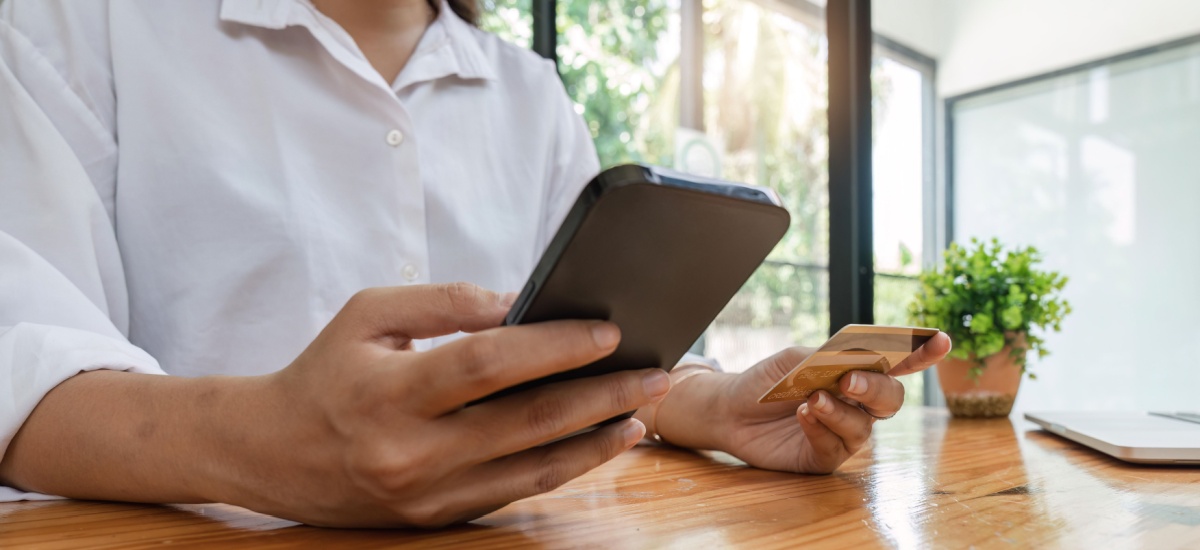 person-sitting-behind-table-holding-phone-and-card