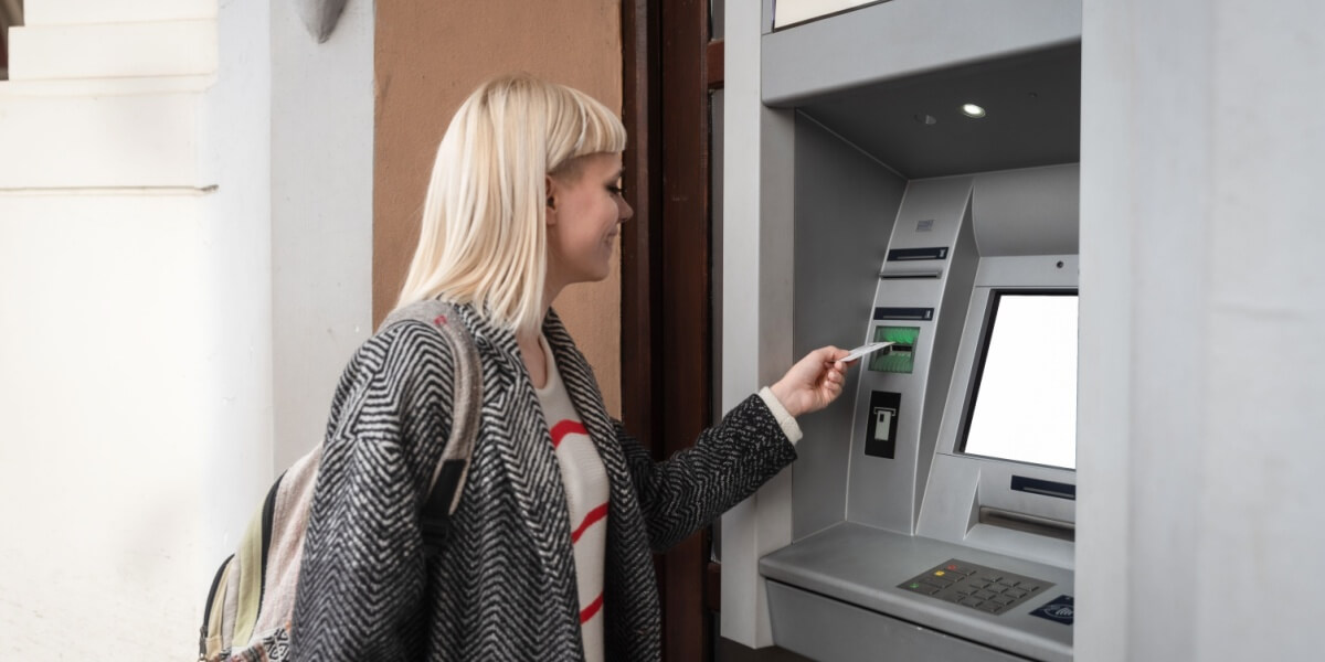 Eine Frau hebt Geld an einem Bancomaten ab