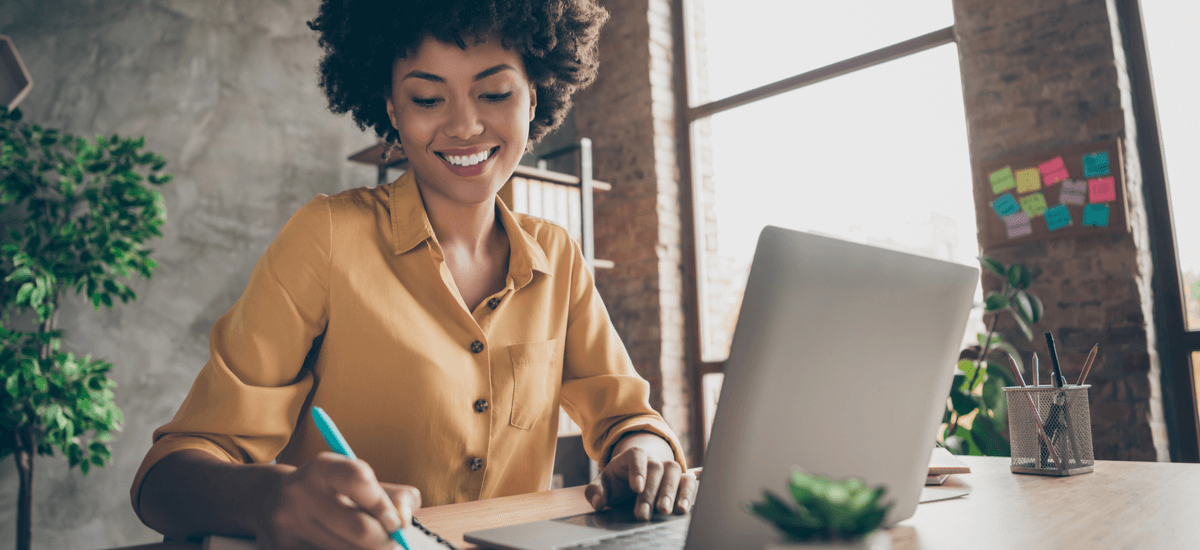 cheerful-business-woman-with-laptop-and-notepad